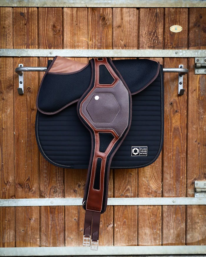 Close-up of a horse saddle hanging on a wooden barn wall.